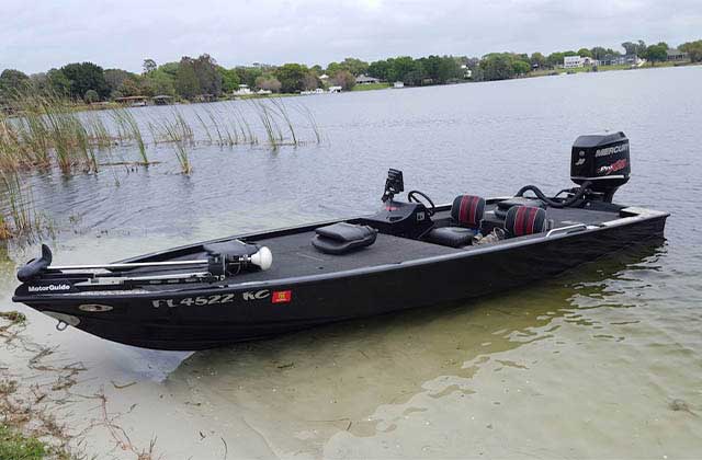 black speedboat with fishing deck and rigging on the bank of a lake at memory makin fishing guides kissimmee
