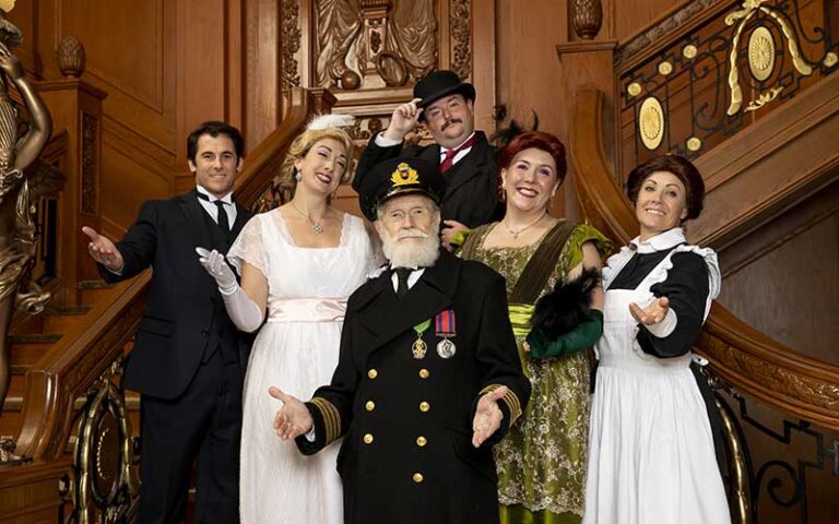 cast of historic characters posing on grand staircase at titanic dinner gala orlando
