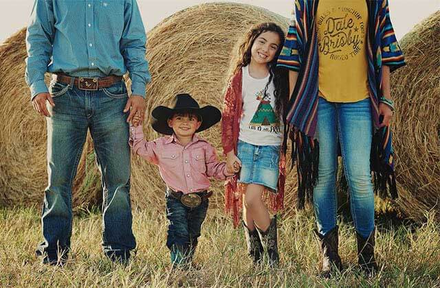 family of four modeling western clothing with hay bales for cavenders western wear orlando