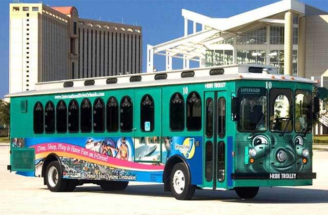 green trolley with upscale high rise hotels behind for i-ride trolley orlando