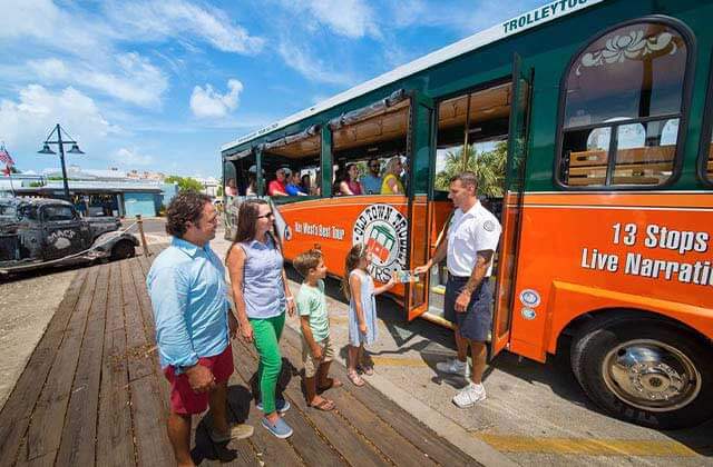guide greets boarders at orange and green trolley bus at historic tours of america key west
