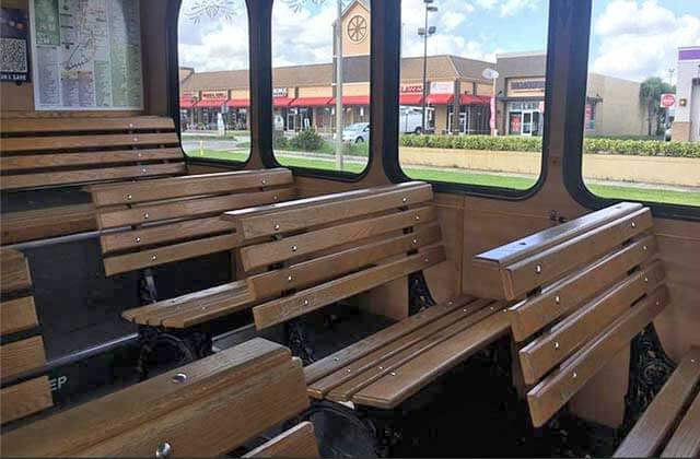inside a trolley bus with wood bench seats and shops outside the window for i-ride trolley orlando