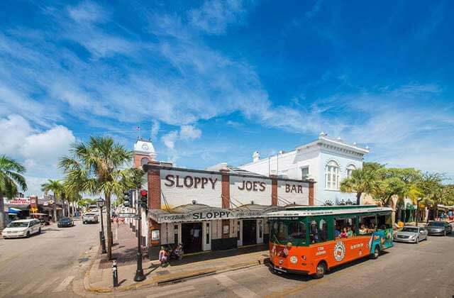 orange and green trolley bus parked at sloppy joes bar at historic tours of america key west