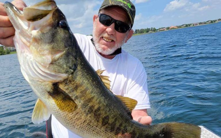 smiling man on boat holding up large mouth bass for makin memories fishing guides kissimmee