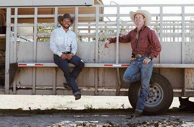 two cowboys lean on a horse trailer for cavenders western wear orlando