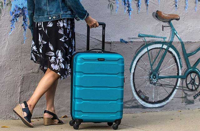 woman rolling blue shell suitcase with street art of bicycle at samsonite stores orlando