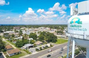 aerial view of small downtown area with trees and lake on horizon and water tower in the foreground right at st cloud destination feature