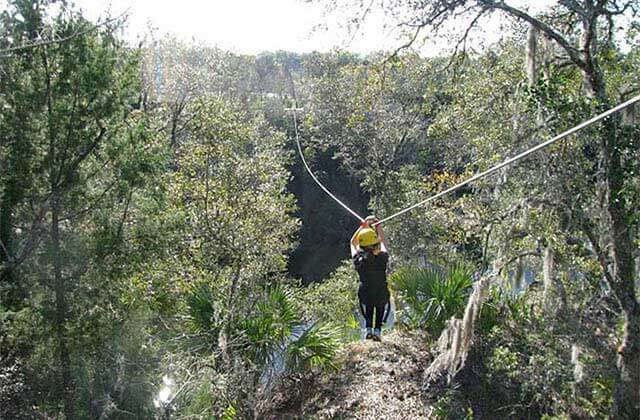 cable with zipliner moving through a tree canopy at the canyons zip line adventure park ocala