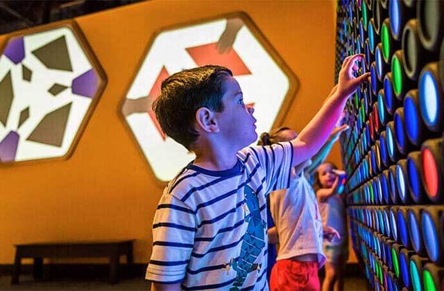 children turn lights on and off on a display wall at orlando science center