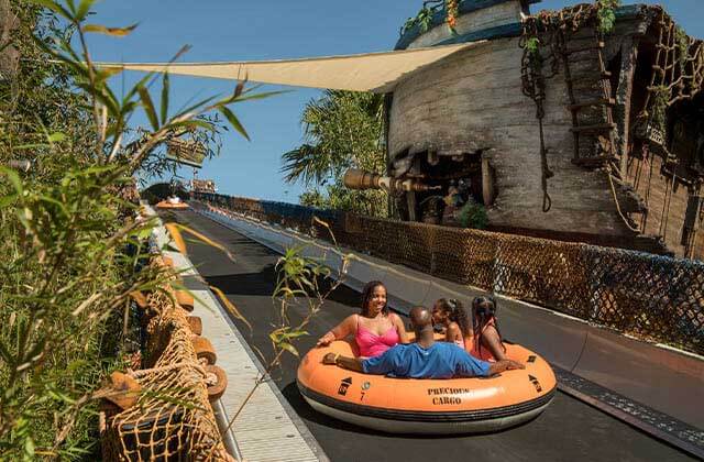 excited family in a raft going up conveyor belt to a ride at disneys typhoon lagoon water park