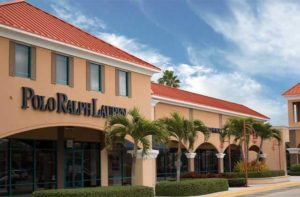 exterior shopping center with salmon colored buildings white columns palm trees and polo ralph lauren storefront at vero beach outlets space coast florida