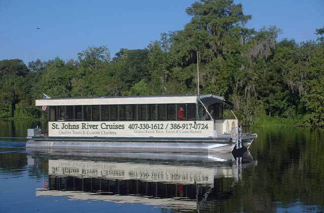 large pontoon tour boat on a river with trees at st johns river cruises at blue spring state park florida