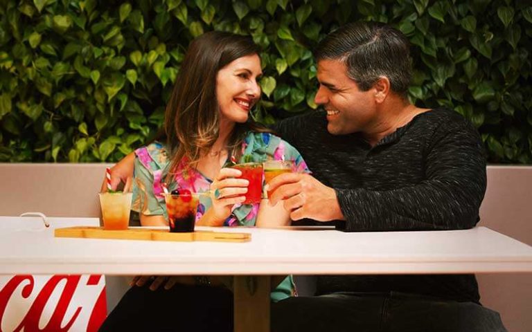 man and woman seated at table sharing drinks with fruit garnish at coca cola store at disney springs