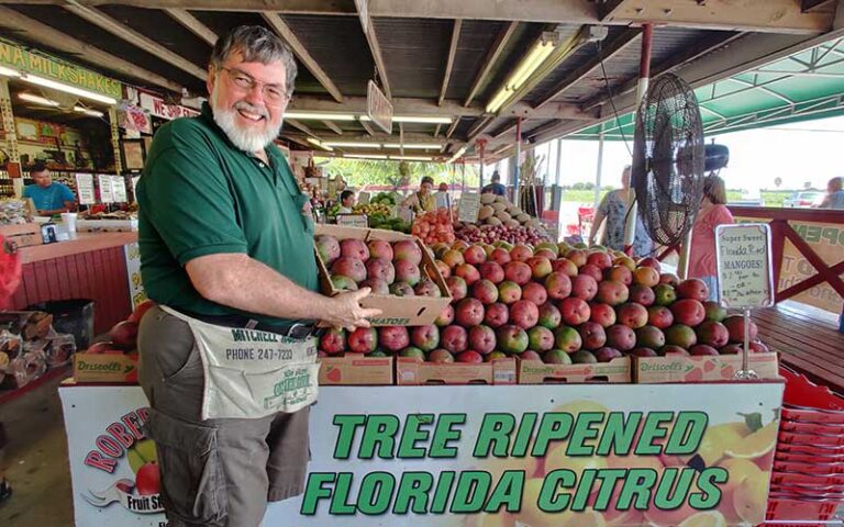 man smiling holding mango fruit stand at historic redland tropical trail