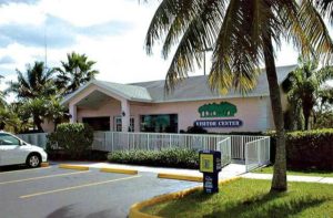 pink exterior front of building with palm trees and parking at tropical everglades visitor center homestead