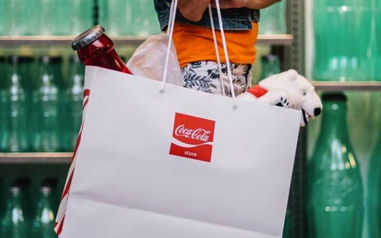 shopper carrying a shopping bag of merchandise at coca cola store at disney springs