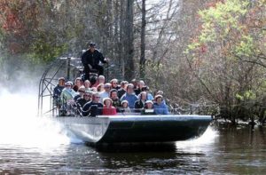 speeding airboat with riders on wetlands at wild bills airboat tours inverness