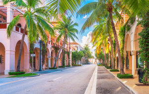 street with spanish colonial style buildings and stately palm trees worth avenue palm beach feature