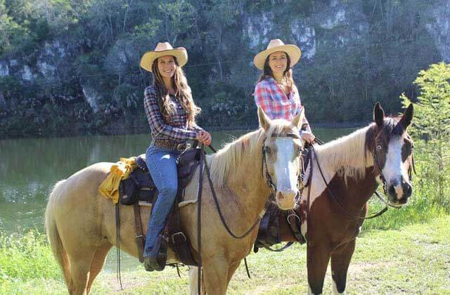 two women on horseback with a canyon lake in the background at the canyons zip line adventure park ocala
