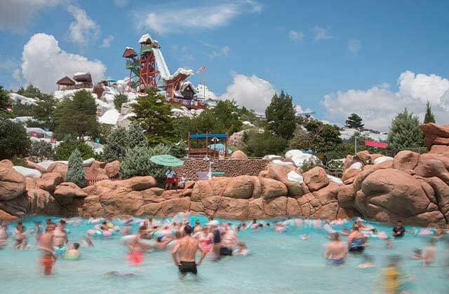 wave pool crowded with ski jump slide above the rocks at disneys blizzard beach water park