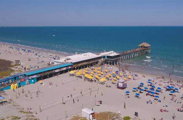 aerial view of a covered pier with a crowded beach at space coast beaches