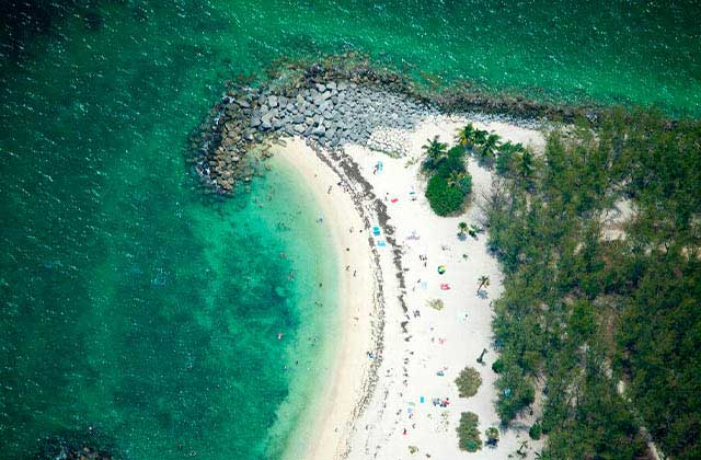 aerial view of rock jetty and shore with green water at florida keys beaches