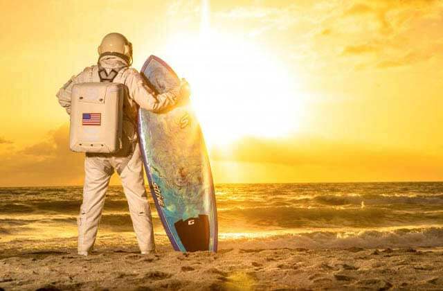 astronaut with surf board and golden sunrise on beach at space coast beaches