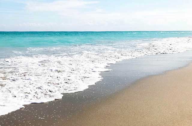 a beach with foamy surf and turquoise water at central east beaches