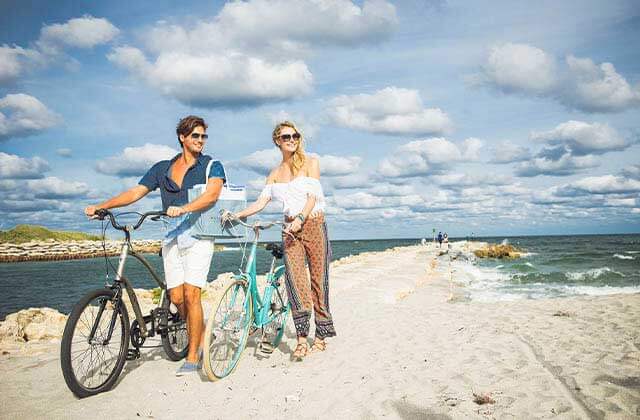 couple pushing bikes along jetty at south east beaches