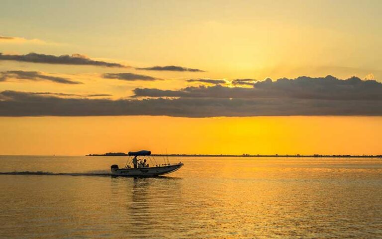 gold sunset over ocean with boat at fort myers sanibel island beaches