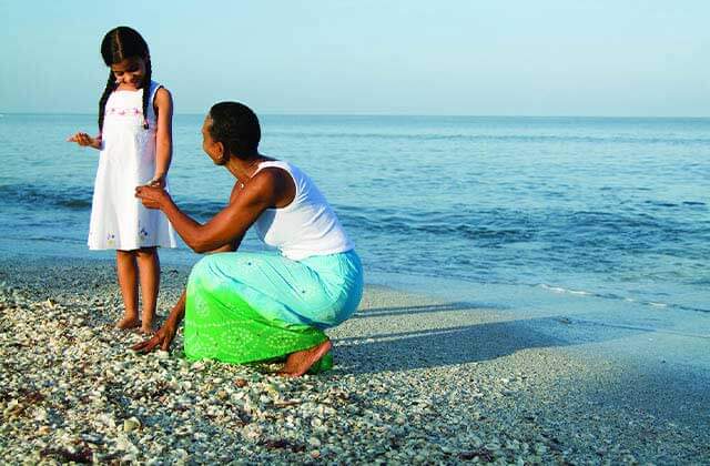 mom picks up shell and shows to daughter at fort myers sanibel island beaches