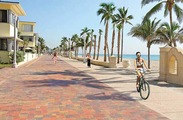 a paved boardwalk along the shoreline with beach houses at floridas hollywood beach