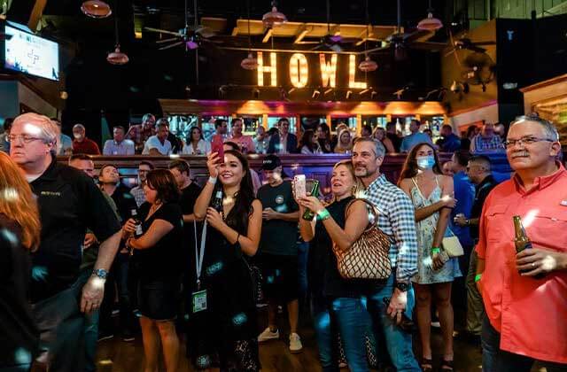 smiling crowd facing stage with disco lighting and howl sign at howl at the moon orlando