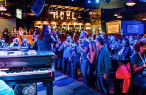 woman with microphone performing with crowd cheering and bar in the background at howl at the moon orlando