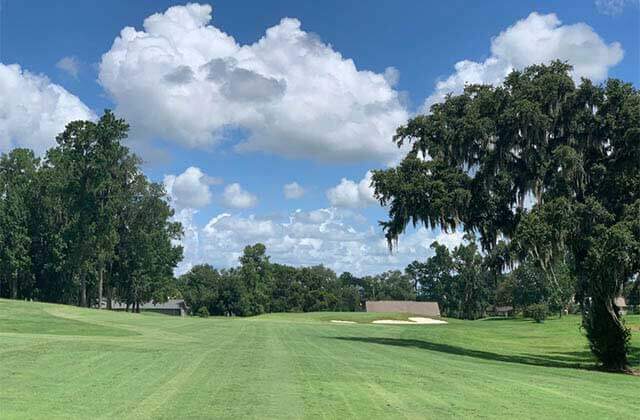 fairway with sand traps trees and cloudy sky at ocala national golf club