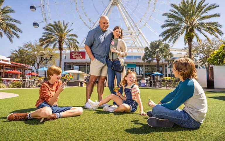 family playing on lawn with wheel behind at the orlando eye icon park