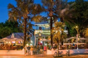 front exterior of restaurant with palm trees at night at hard rock cafe key west