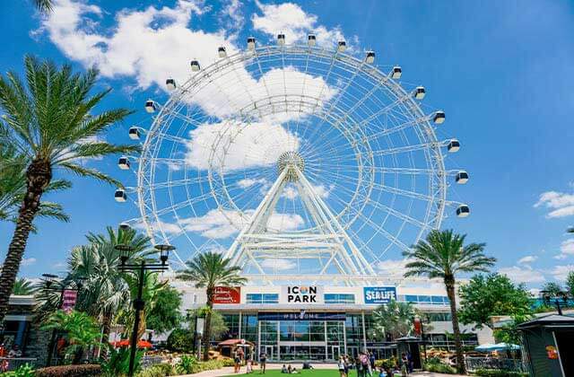 observation wheel view from front lawn with palm trees and cloudy blue sky at the wheel at icon park orlando