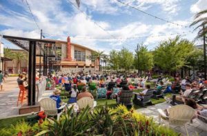 outdoor promenade area with lawn chairs field and stage at celebration pointe gainesville
