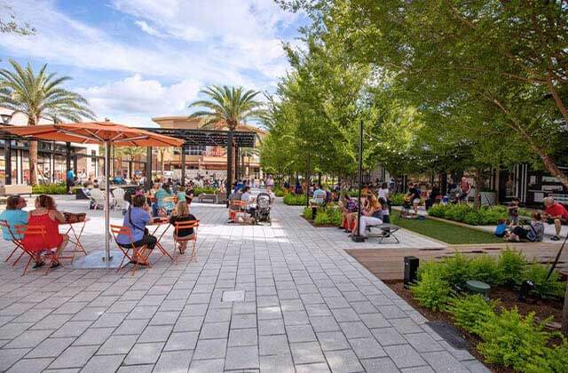 people seated under umbrellas with paved area and landscaping at celebration pointe gainesville