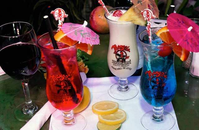 round of colorful tropical drinks with umbrellas and fruit at mangos tropical cafe south beach miami