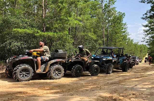 row of atvs drive through forest at world adventures ocala