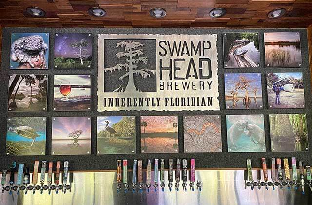 sheet metal art sign above a row of dozens of taps at swamp head brewery gainesville