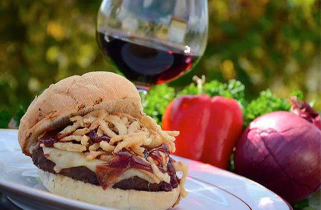 signature burger and glass of red wine with red pepper and onion garnish at lakeridge winery vineyards orlando