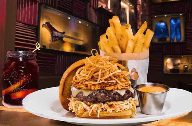 signature burger with fried onions entree with rock decor behind at seminole hard rock hotel casino hollywood florida