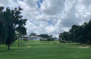 smooth rolling fairway flanked with trees and clubhouse in the background at ocala national golf club