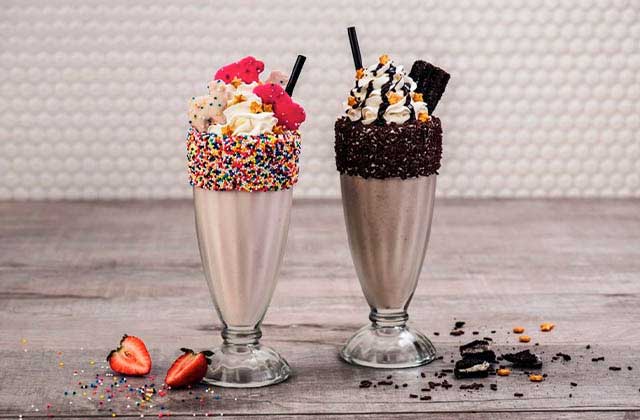 two milkshakes with sprinkles and toppings in glass and metal parfait containers at hard rock cafe key west