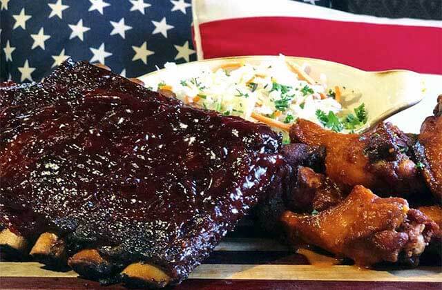 barbecue ribs wings and slaw entree with american flag background at american social