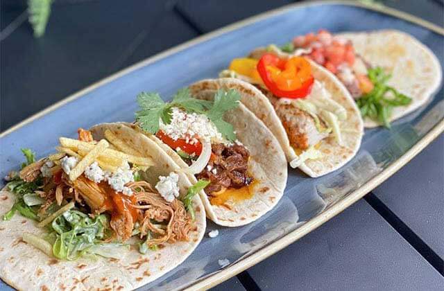 blue plate with four varieties of gourmet tacos at american social
