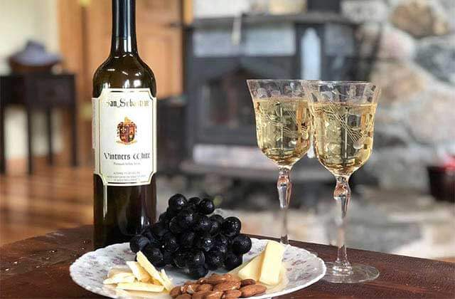 bottle and two glasses with a plate of grapes cheese and almonds at san sebastian winery st augustine